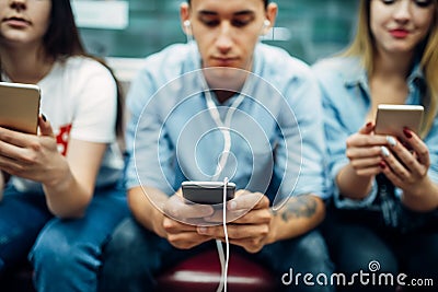 Modern youth using phones in subway, addiction Stock Photo