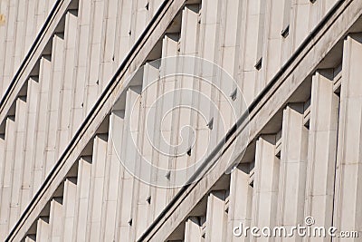 A modernist facade with repeating vertical concrete elements, creating rhythmic patterns and dynamic diagonal shadows Stock Photo