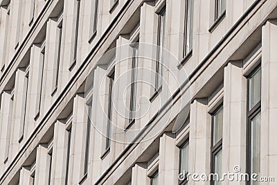 A modernist facade with repeating vertical concrete elements, creating rhythmic patterns and dynamic diagonal shadows Stock Photo