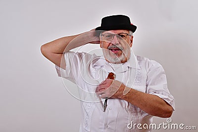 Modest senior man smiling and hanging on to his hat Stock Photo