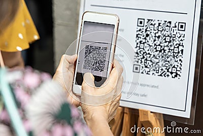 Modified inactive QR Code used. Person scanning QR code with smartphone to register details before enter outlet to comply with Stock Photo
