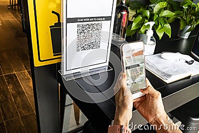 Modified inactive QR Code used. Person scanning QR code with smartphone to register details before enter outlet to comply with Editorial Stock Photo