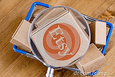 Modified photo of Etsy logo on a box under magnifying glass in the shopping cart Editorial Stock Photo