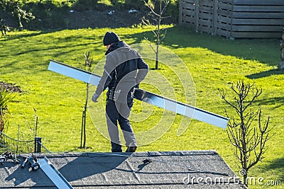 Moers , Germany - February 05 2018 : Roofer balancing on roof with metal facing Editorial Stock Photo