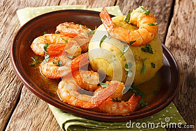Mofongo mashed plantains, garlic and chicharron served with shrimps and broth close-up on a plate. horizontal, rustic style Stock Photo