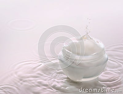 Moisturizing cosmetic cream on the pink milk background with milk splash and drops Stock Photo