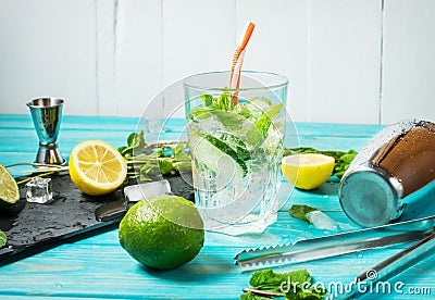 Mojito cocktail with lime and mint in highball glass on a blue wood table. Drink making tools and ingredients for cocktail Stock Photo