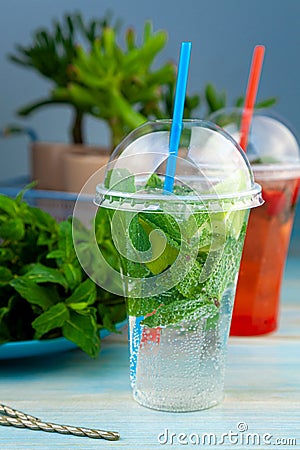 Mojito and Lemonade summer cold drink in a plastic glass with a straw. Coctail with mint, lemon, lime and ice. Serve at the bar. Stock Photo