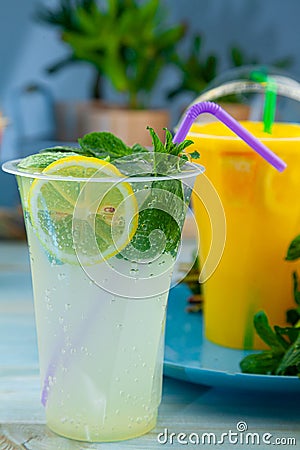 Mojito and Lemonade summer cold drink in a plastic glass with a straw. Coctail with mint, lemon, lime and ice. Serve at the bar. Stock Photo