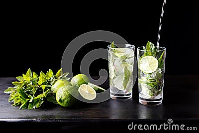 Mojito traditional beach refreshing cocktail alcohol drink in glass bar preparation pouring soda water, lime, mint Stock Photo