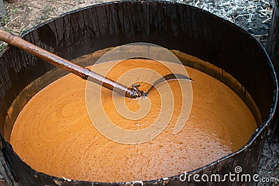 Molasses is being made from sugarcane juice in a large iron pot in a rural area Stock Photo