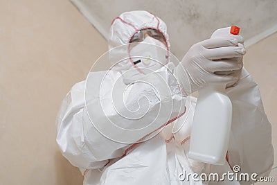 Mold removal. A man cleans mold from a wall using a sprayer and a sponge. Insect and mold removal company. Cleaning Specialist. Stock Photo