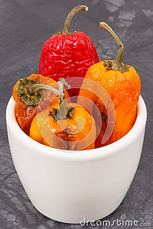 Moldy and wrinkled peppers in white bowl. Unhealthy, decompose, spoiled vegetable Stock Photo