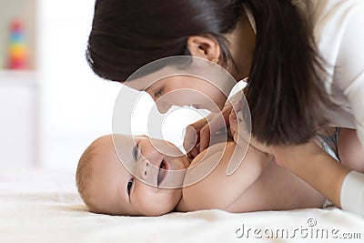 Mom and baby boy in diaper playing in sunny bedroom. Mother and little child relaxing at home. Family having fun Stock Photo