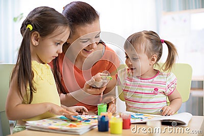 Mom and children draws with colored paints. Games with child affect early kids development. Stock Photo