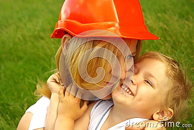 Mom in the construction helmet with love hugging happy daughter Stock Photo