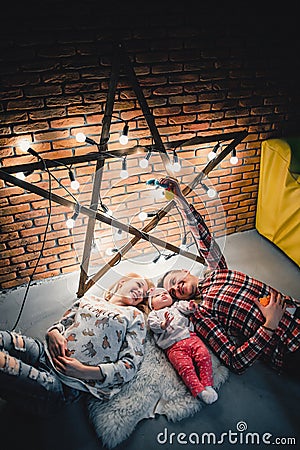 mom, dad and baby lie on a woolen carpet and smile Stock Photo