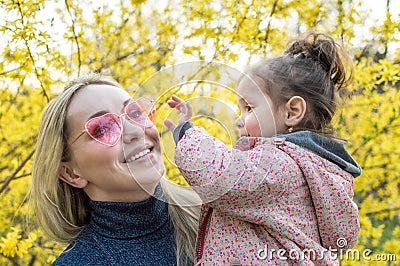 Mom and daughter. the girl tries to take off sunglasses from her mother. sunglasses in the shape of heart Stock Photo