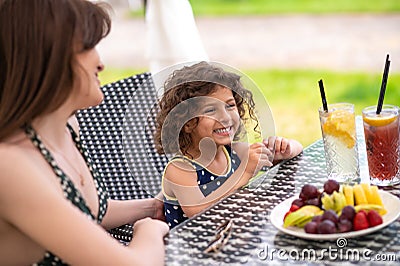Mom and daughter having fruits and looking happy Stock Photo