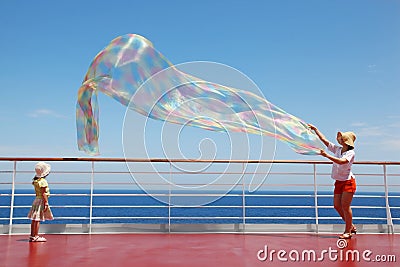 Mom and daughter play with chiffon scarf on deck Stock Photo