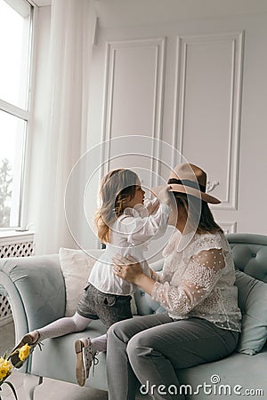 Mom and daughter in white blouses playing in the studio with daffodils. mother`s day Stock Photo