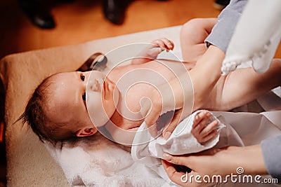 Mom dress their child on a table in the Church. the ordinance of baptism. Stock Photo