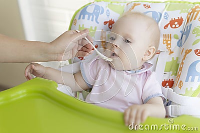 Mom feeds the baby with a spoon Stock Photo