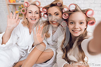 Mom, grandmother and girl in curlers do selfie on the phone. Stock Photo