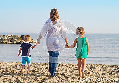 Mom and her children walk hand in hand at the beach Stock Photo