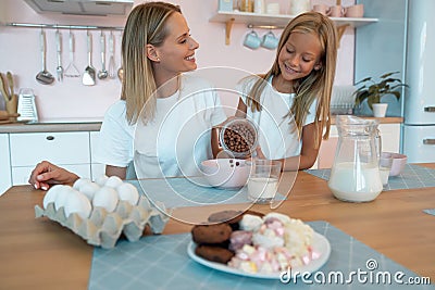 Mom with her daughter eating chocolate flakes. have a good time together, dressed alike Stock Photo