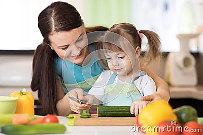 Mom with her daughter in kitchen preparing healthy food with fresh vegetables, home parenting lifestyle Stock Photo