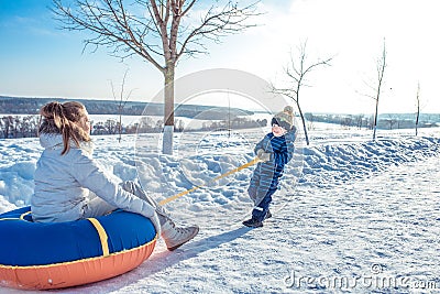 Mom with her little son 3 years old, riding Tubing on a sunny day in city in winter. Play Snorkeling. Happy Scrabing Stock Photo