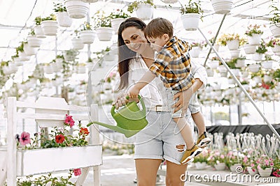 Mom helps her little son water flowers in the greenhouse Stock Photo