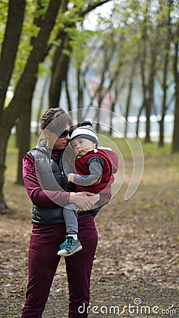 Mom holds a tired little boy in her arms in the park Stock Photo