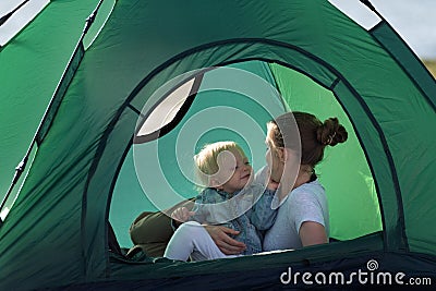 Mom hugs baby while lying in tent. Camping rest. Tourism, travel, outdoor activities Stock Photo