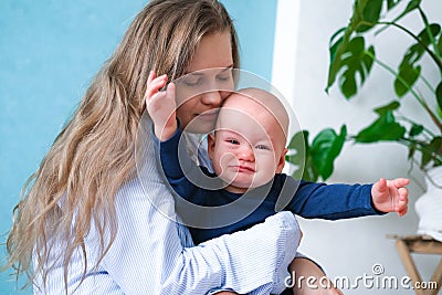 Mom hugs crying moody kid tantrum. Little baby child on mother hands. Family life, motherhood Stock Photo