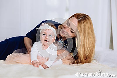 Mom hugs her little daughter who tries to tell her first words. A woman looks at her child with love. Stock Photo