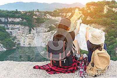 Mom and kid holding maps and travel backpacks sitting victorious facing on the grand canyon for education nature. Stock Photo