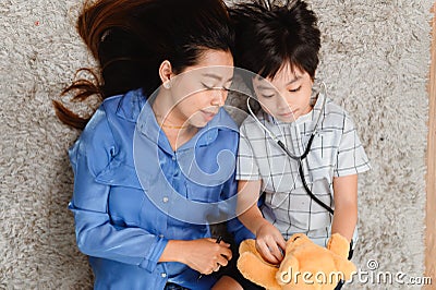 Mom and kid playing as doctor together in living room. Lifestyle and family activity. Asian mother with son Stock Photo