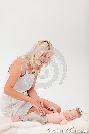 Mom laughs and plays with her little lying son Stock Photo