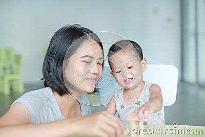 Mom and little baby boy playing wood blocks tower game for Brain and Physical development skill in a classroom. Focus at children Stock Photo