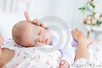 Mom and newborn baby sleep together, mom puts baby to sleep on the bed in the bedroom, the concept of motherhood and healthy sleep Stock Photo