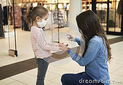 Mother sanitizing her daughter`s hands with antibacterial hand spray Stock Photo