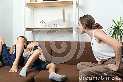 Mom scolds the sons who are lying on couch and lounging around. Raising teenage sons. Mom scolds children Stock Photo