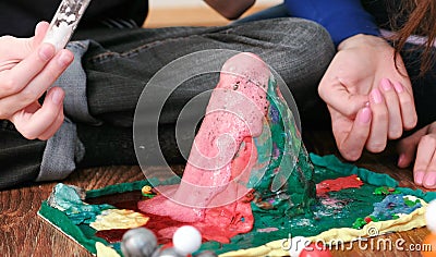Mom and son`s hands make experience with plasticine volcano at home. Chemical reaction with gas emission. Stock Photo