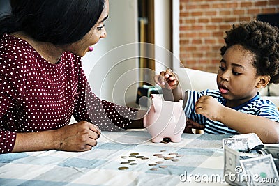 Mom and son saving money to piggy bank Stock Photo