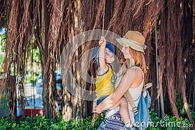 Mom and son on Vietnam travelers are on the background Beautiful tree with aerial roots Stock Photo