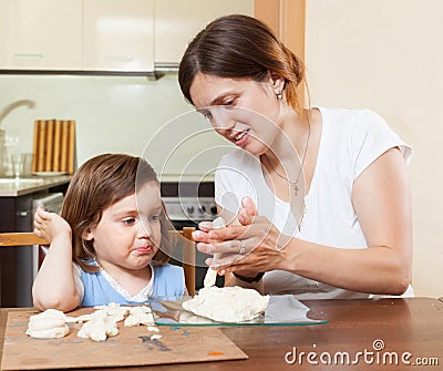 Mom teaches the girl to mold dough figurines Stock Photo