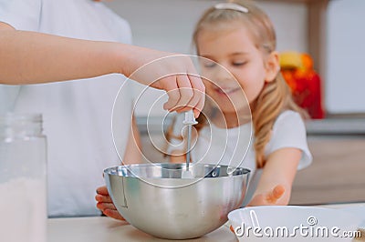 Mom teaches her daughters to cook dough in the kitchen Stock Photo