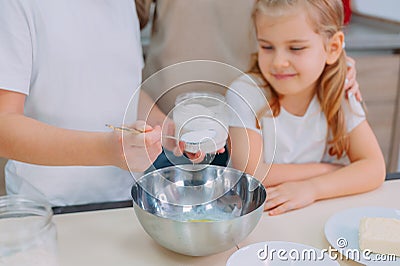 Mom teaches her daughters to cook dough in the kitchen Stock Photo